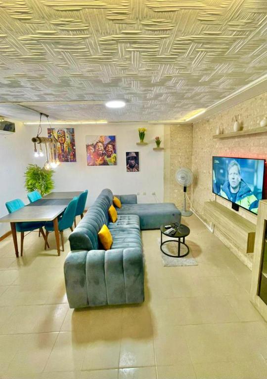 Una sala de estar con un sofá azul y una mesa. en Appartement Grace, en Abiyán