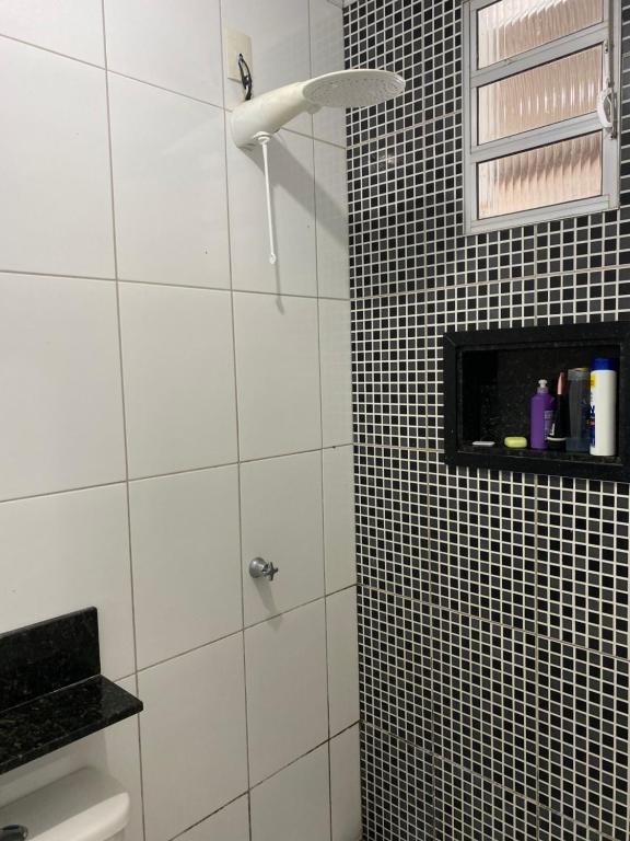 a bathroom with a shower with black and white tiles at Casa temporada Guarapari in Guarapari