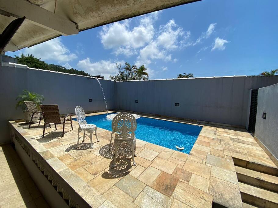 a patio with chairs and a swimming pool at Casa com Piscina na Enseada in Guarujá