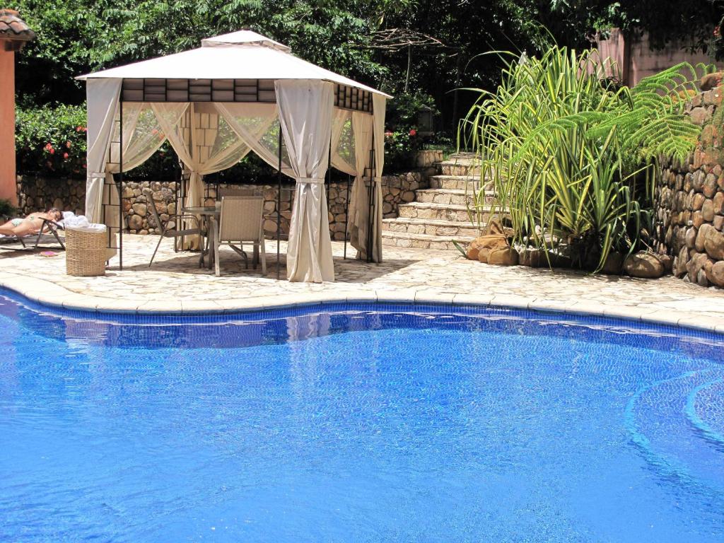 uma piscina com um guarda-sol e um gazebo em Los Almendros de San Lorenzo em Suchitoto