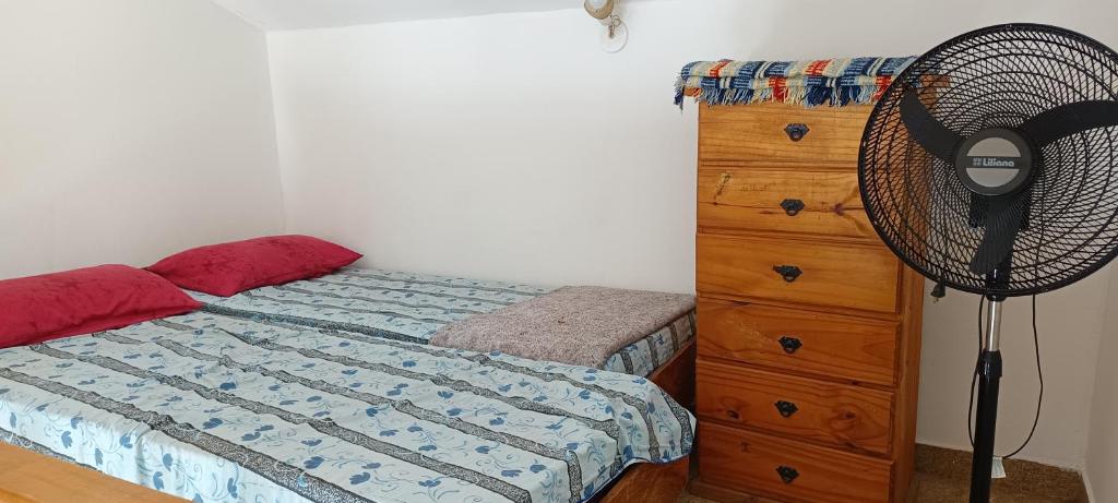 a bedroom with a bed with a fan and a dresser at El nuevo amanecer mar de ajó in Mar de Ajó