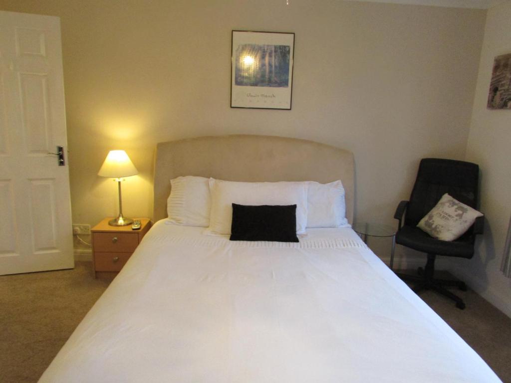 a bedroom with a large white bed and a chair at SleepNeat in Ascot