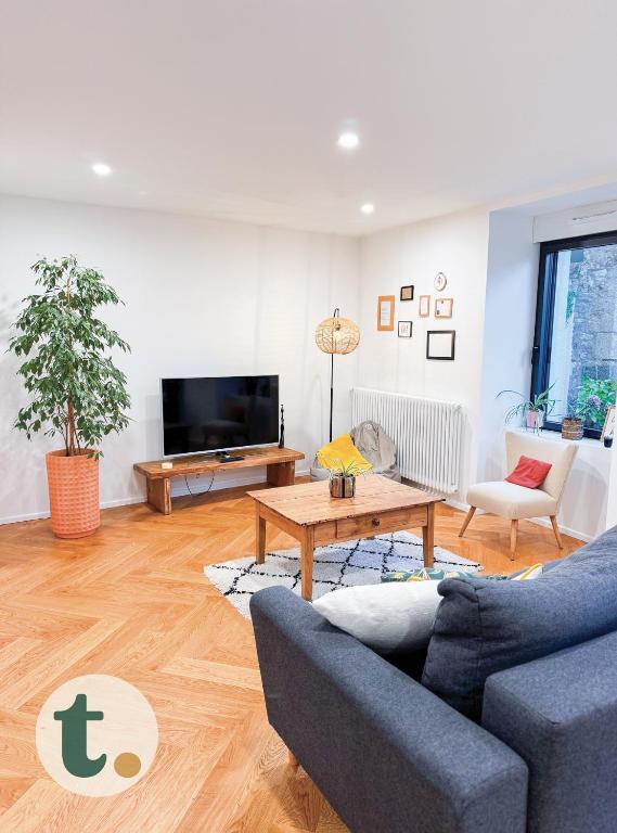 un salon avec un canapé bleu et une table dans l'établissement Tranquiloue - Maison au charme d'Antan - PuyduFou, à Les Landes-Génusson