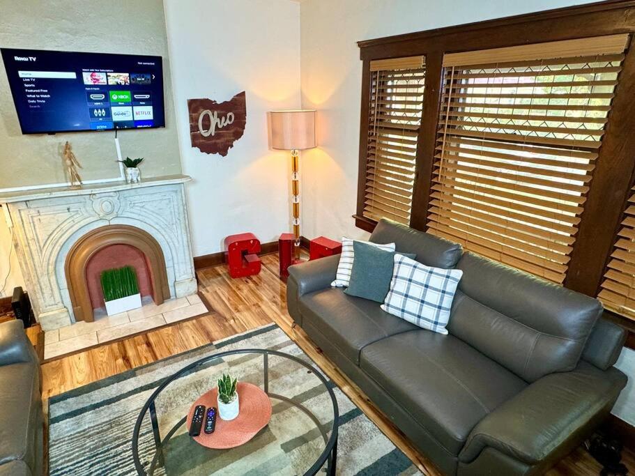 ein Wohnzimmer mit einem Ledersofa und einem Kamin in der Unterkunft The House Hotels - West 47th 1 - Two Bedroom Ohio in Cleveland