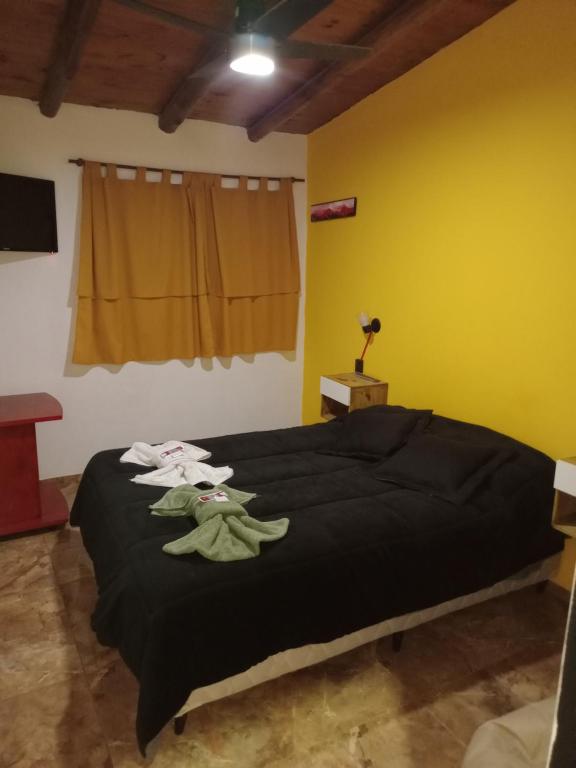 a bedroom with a bed with black sheets and yellow walls at ALQUILER POR DIA EN MALARGÜE 2 Céntrico in Malargüe