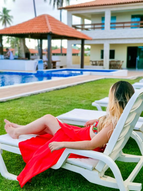 a woman in a red dress laying in a lawn chair at Pousada recanto porto tropical in Sirinhaém