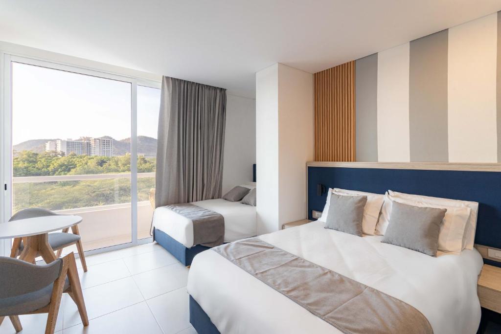 une chambre d'hôtel avec un grand lit et une fenêtre dans l'établissement Increible Apartasuit a solo 3 min de la playa, à Santa Marta
