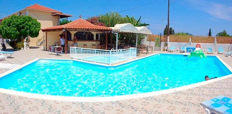 uma grande piscina azul em frente a uma casa em Zante 523 em Laganas