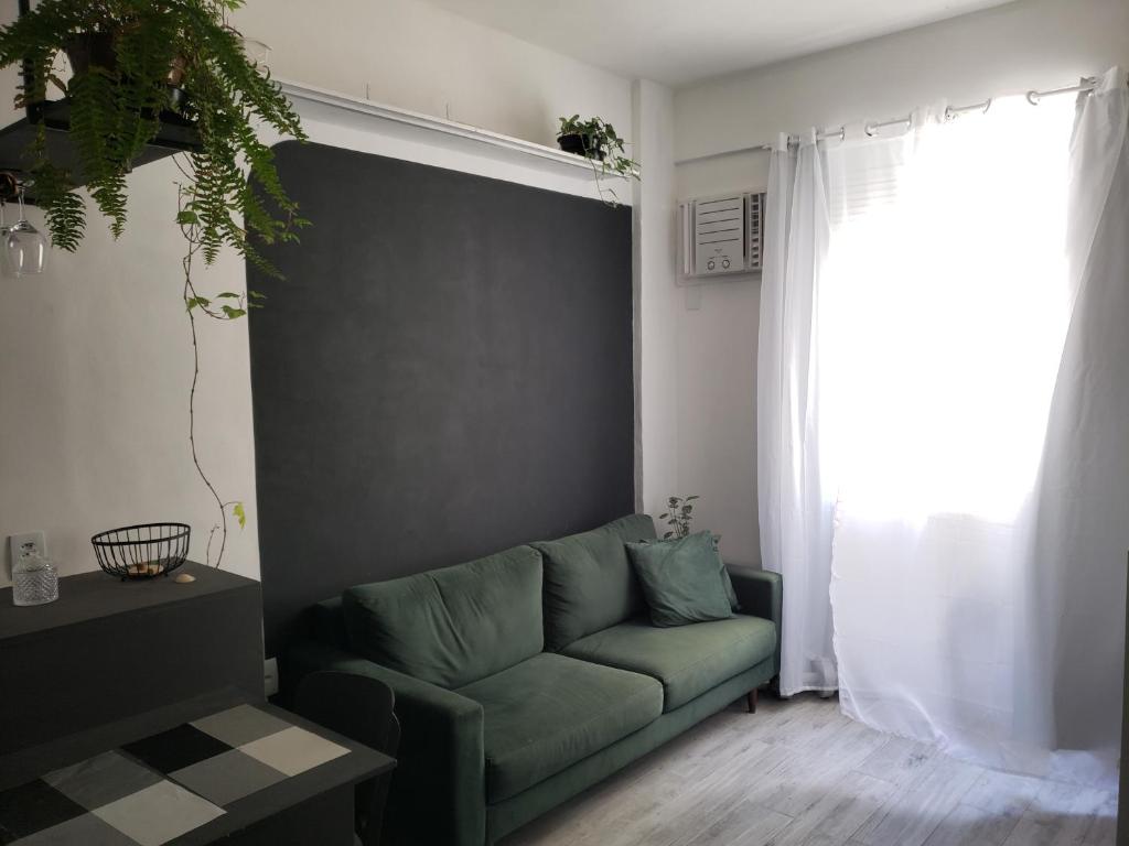 uma sala de estar com um sofá verde e uma janela em Studio Praia de Botafogo no Rio de Janeiro