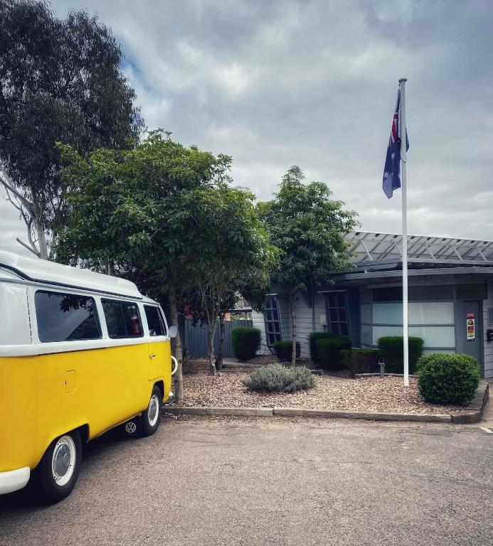 a yellow and white van parked in front of a house at Bacchus Marsh Caravan Park in Bacchus Marsh