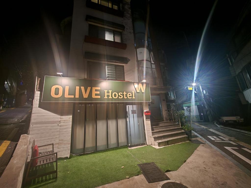 een gebouw met een bord dat 's nachts een levend ziekenhuis leest bij Olive hostel W in Seoul