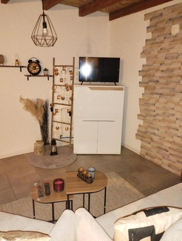 un salon avec une télévision au-dessus d'un réfrigérateur dans l'établissement jolie maison campagnarde, à Gevrolles