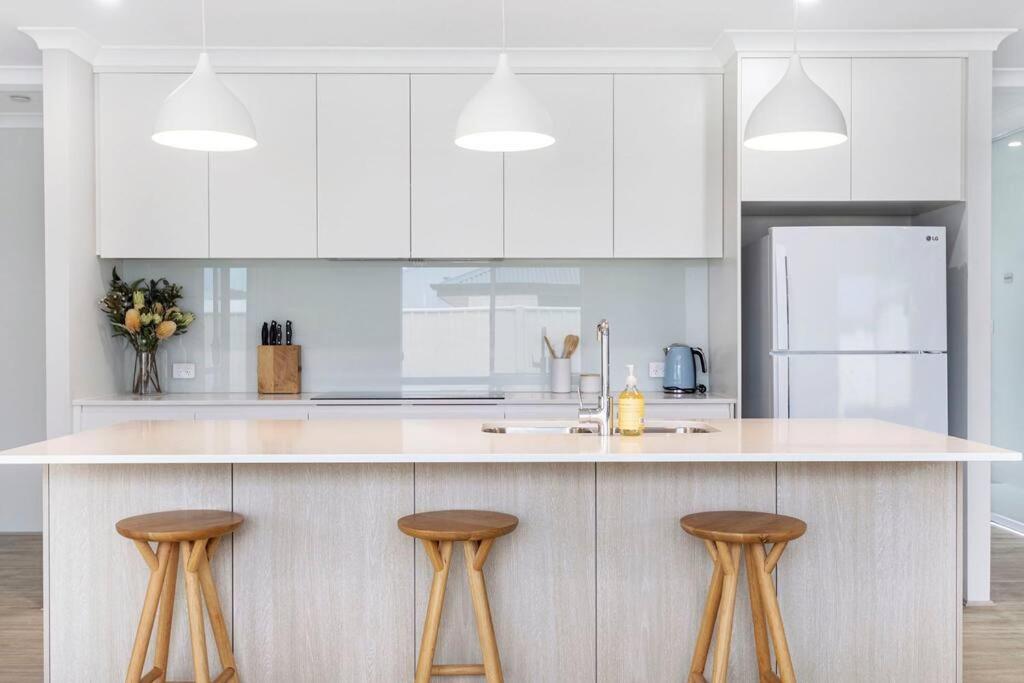 eine Küche mit weißen Schränken und einer Theke mit Stühlen in der Unterkunft Brand New Home Dunsborough in Dunsborough