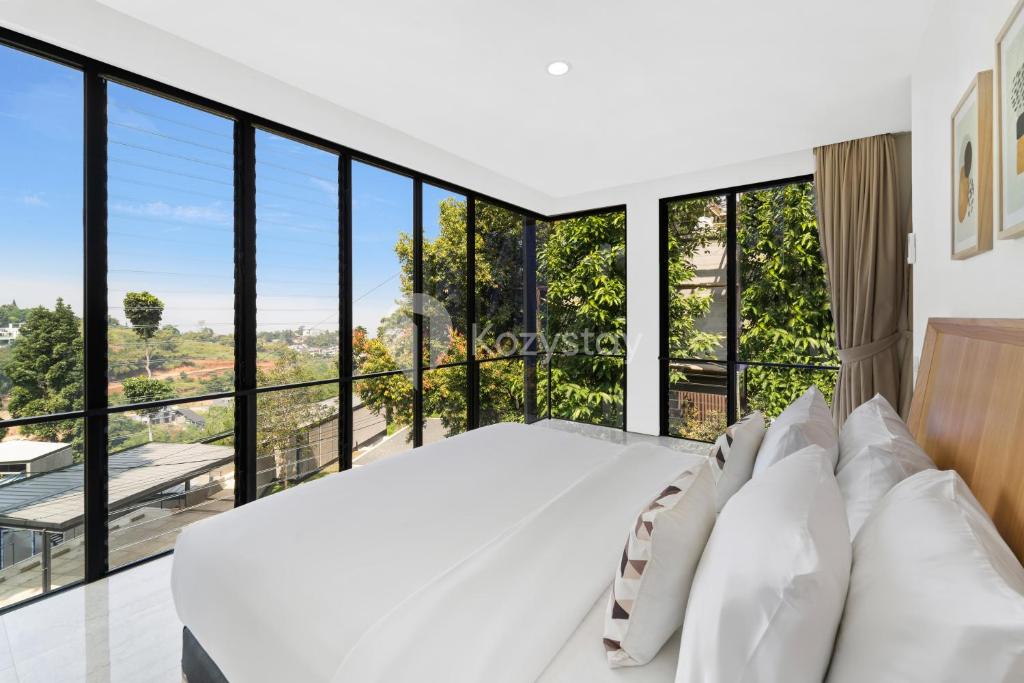 Schlafzimmer mit einem weißen Bett und großen Fenstern in der Unterkunft Sukha by Kozystay - Dago in Bandung