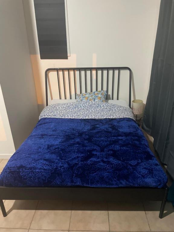 - un lit avec une couette bleue dans l'établissement Maison T 2 meublé confort proche aéroport, à Pusignan