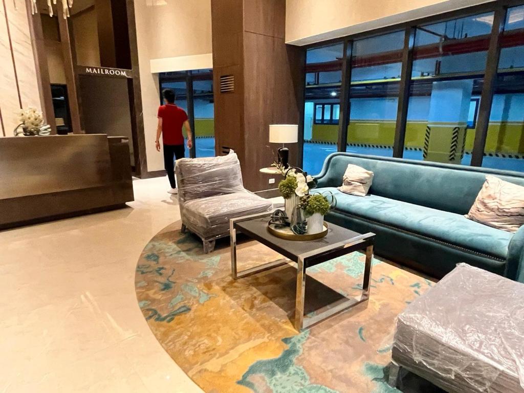 Un vestíbulo con un sofá azul y una mesa y sillas. en Okada complex 1BR with Balcony View, Sofa, Queen Bed and WIFI 8J, en Manila