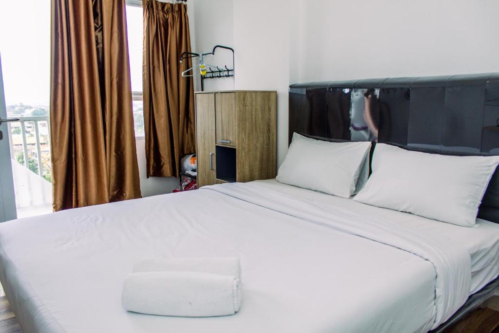 a bedroom with a white bed with white pillows at Comfort Stay Studio Room at Poris 88 Apartment By Travelio in Tangerang