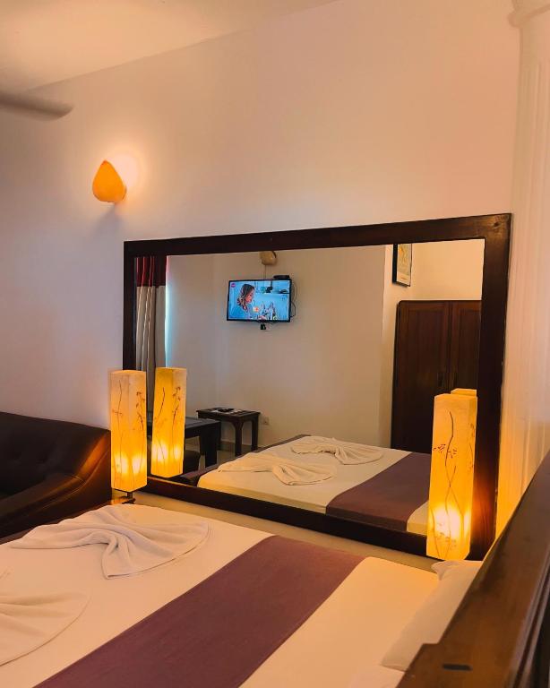 a hotel room with two beds and a mirror at Lavinia Blue Hotel in Mount Lavinia