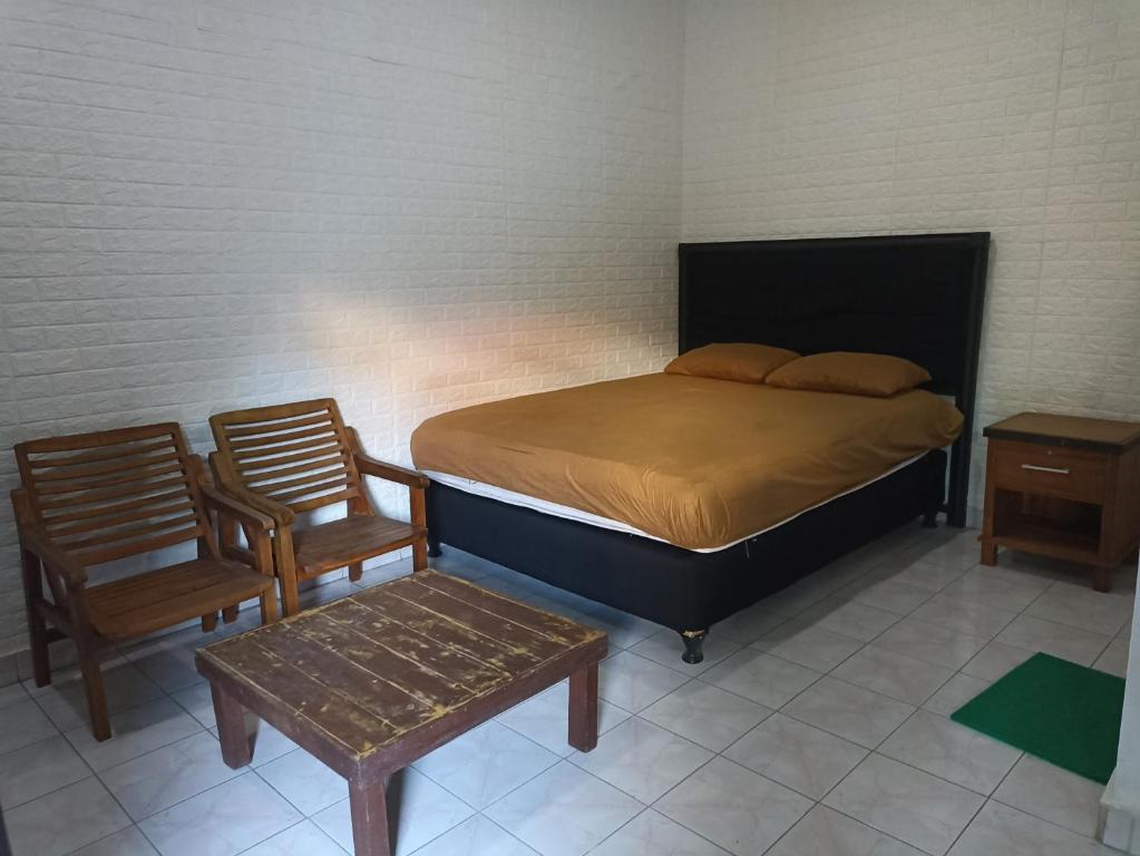 Tokomang Homestay في ليغِيان: غرفة نوم بها سرير وكرسيين وطاولة