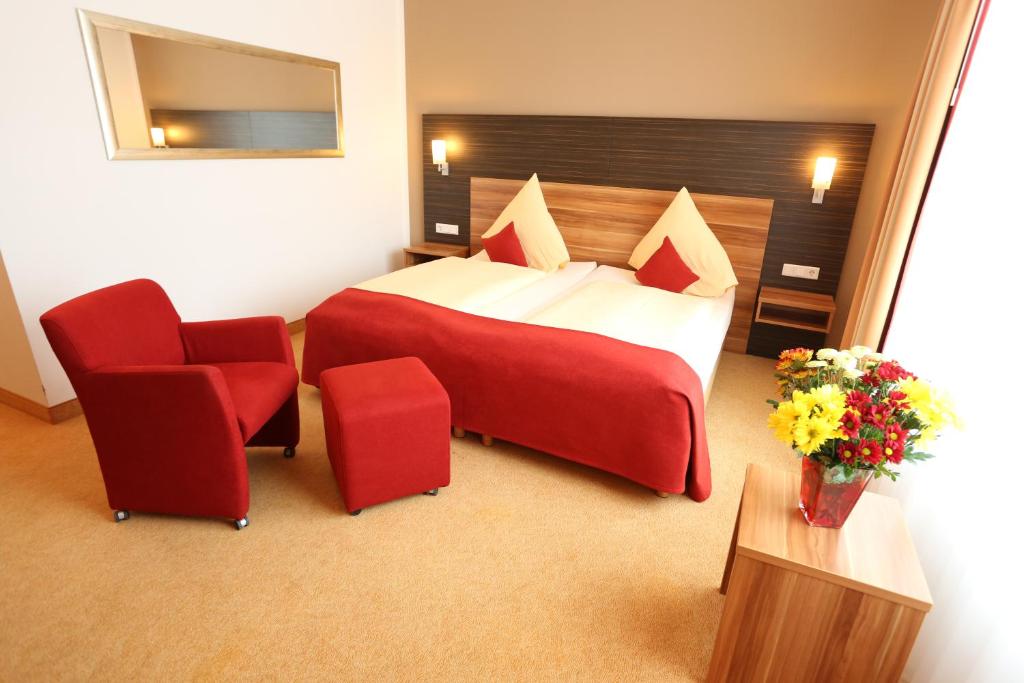 デュースブルクにあるHotel Sittardsbergのベッドと椅子付きのホテルルーム