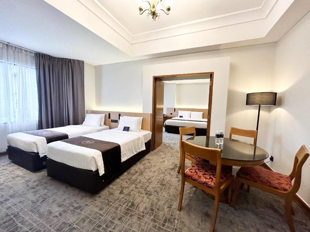 A twin room with a round dining table, upholstered chairs and a mirrored opening toward another bed area.