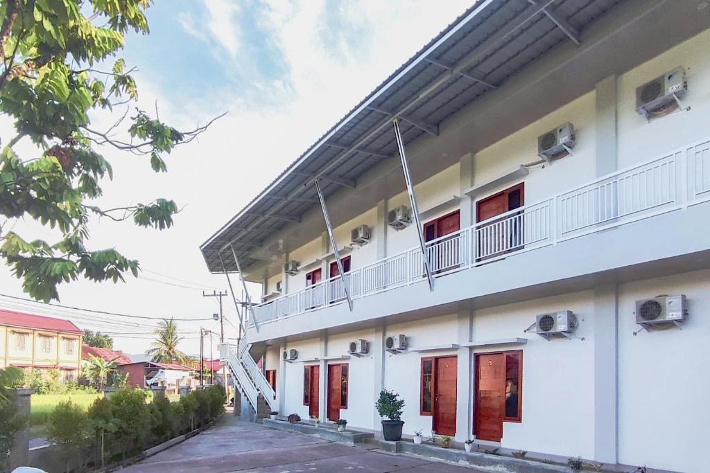 a white building with red doors and a balcony at RedDoorz Syariah at Djaya Guest House Padang in Padang