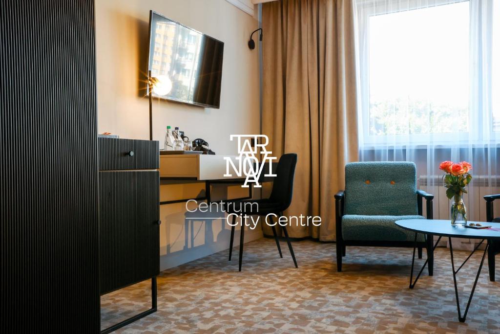 Una sala de estar con una mesa y sillas y una ventana. en Hotel Tarnovia, en Tarnów