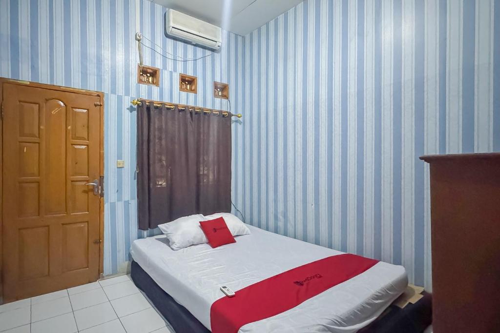 a bedroom with a bed with a red towel on it at RedDoorz at Kuning GH Jatinangor in Sayang