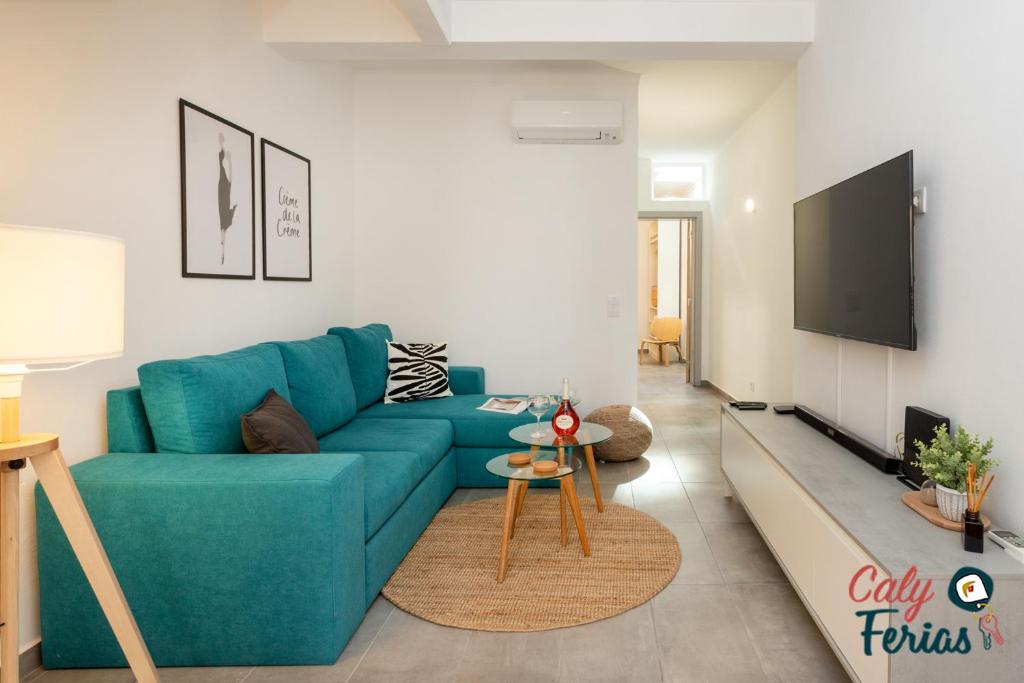 un salon avec un canapé bleu et une télévision à écran plat dans l'établissement La petite maison de Armação de Pêra By Calyferias, à Armação de Pêra