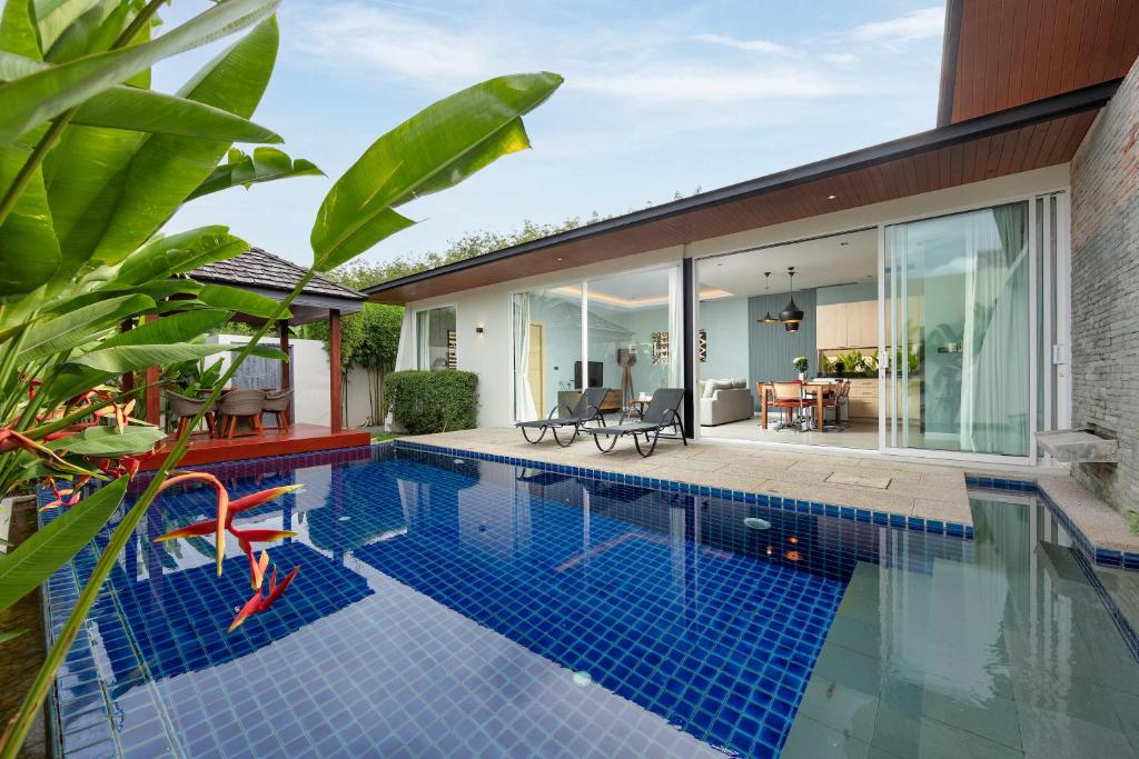 an indoor swimming pool with a house with glass walls at Solano Tropical 3BR Pool Villa at Bang Tao in Layan Beach