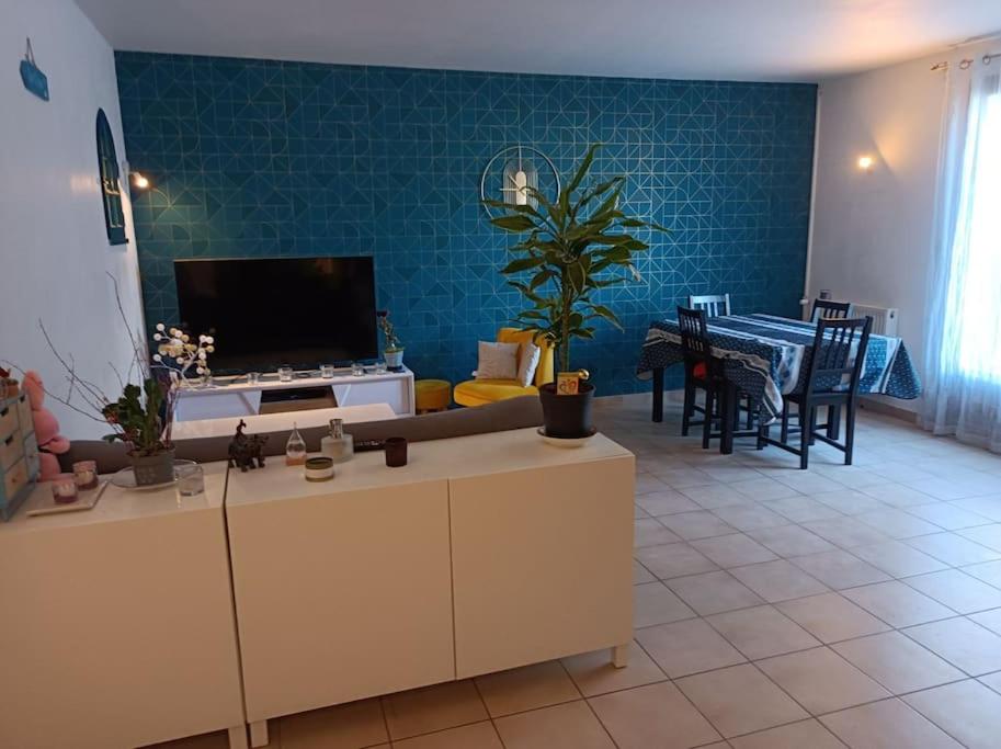 Il comprend un salon doté d'une télévision et d'une table avec des chaises. dans l'établissement maison face au château, à Chaumont-sur-Loire