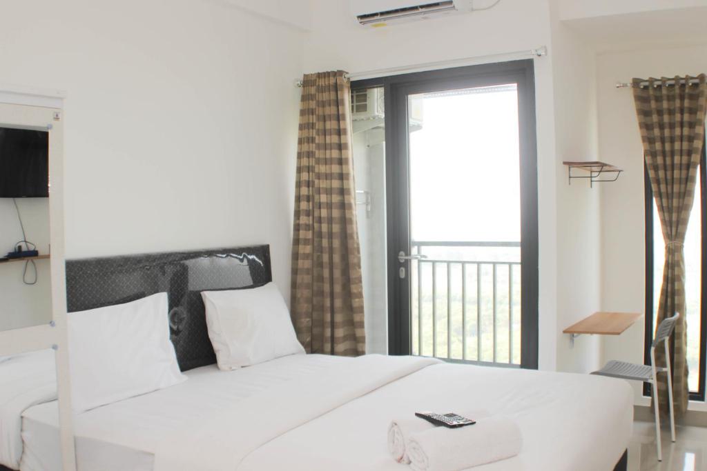a bedroom with a white bed and a balcony at Fancy and Nice Studio Apartment at Sayana Bekasi By Travelio in Bekasi