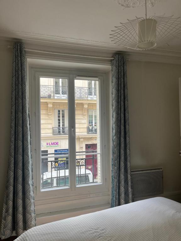 BerthouvilliersCozy appartement near Opera and Galeries Lafayette Haussmann的一间卧室设有窗户,享有建筑的景色