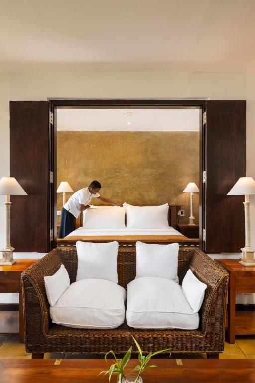 a man preparing a bed in a hotel room at Jetwing Beach in Negombo