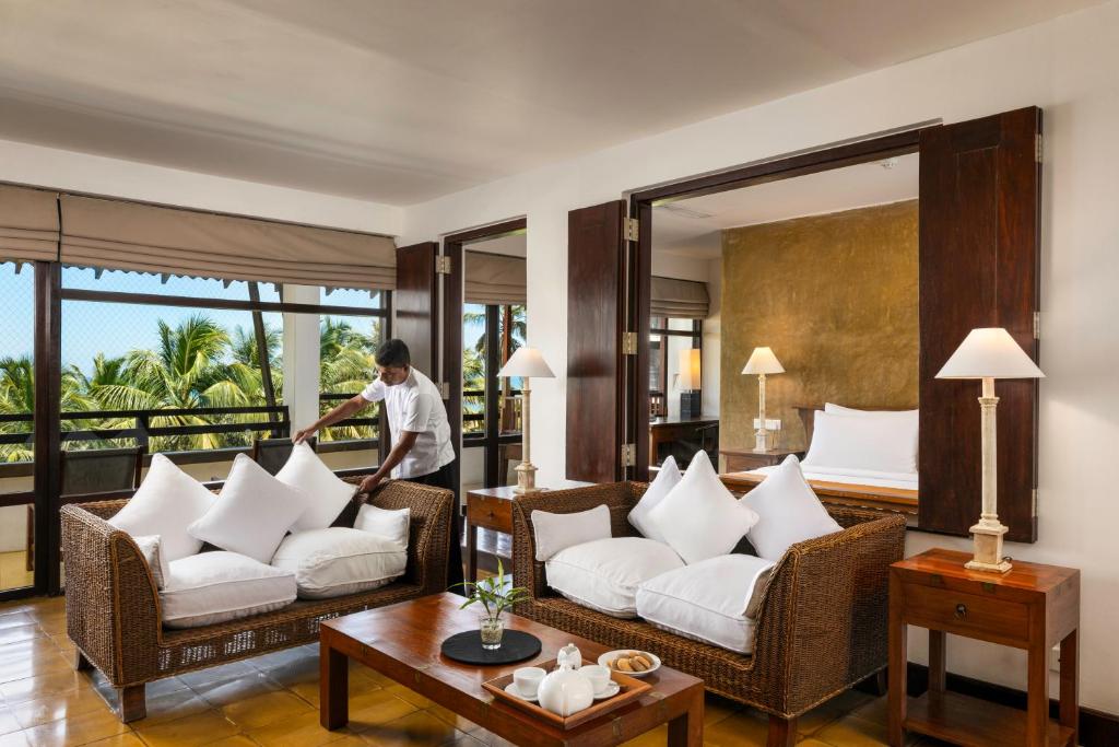 a man cleaning a living room with white furniture at Jetwing Beach in Negombo