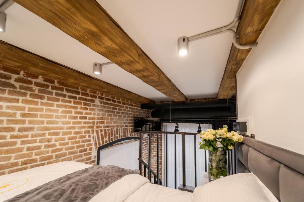 a room with a brick wall and a vase of flowers on a balcony at Royal mini apart-hotel on Kovzhyna in Lviv