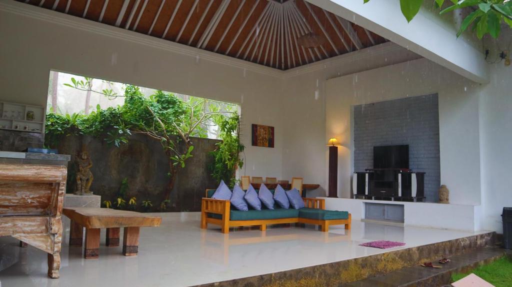 Pranajaya loka villa في تيجاكولا: غرفة معيشة مع أريكة وطاولة