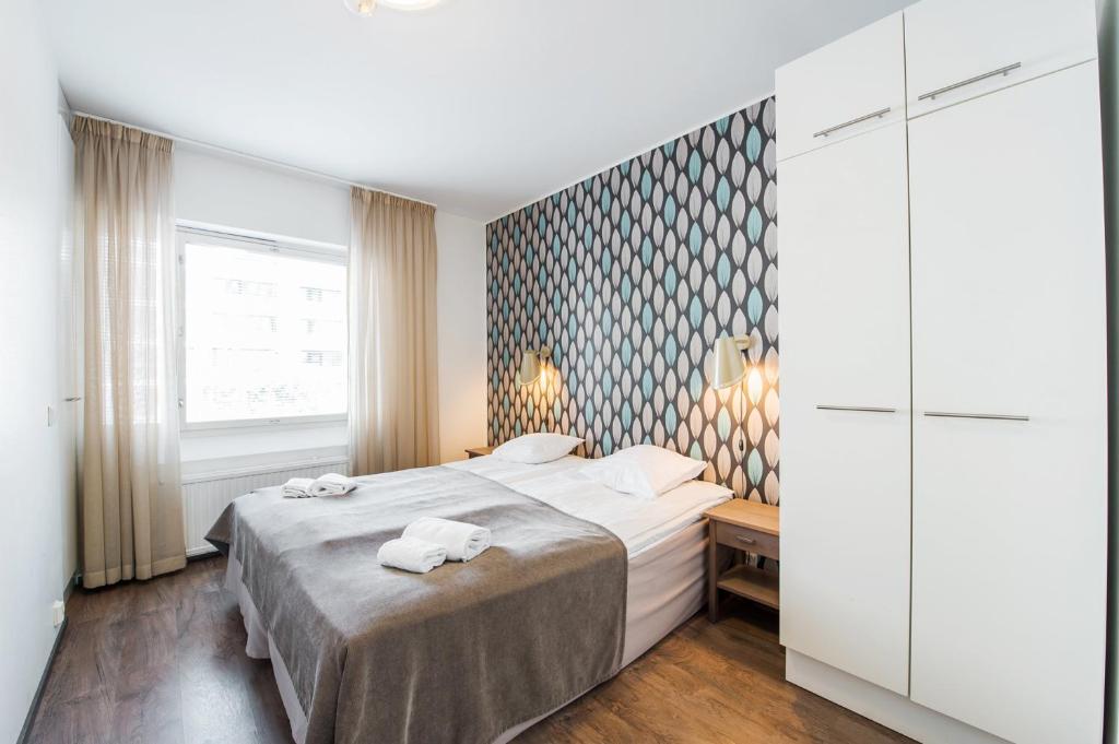 a bedroom with a bed with two towels on it at Forenom Serviced Apartments Helsinki Lapinlahdenkatu in Helsinki