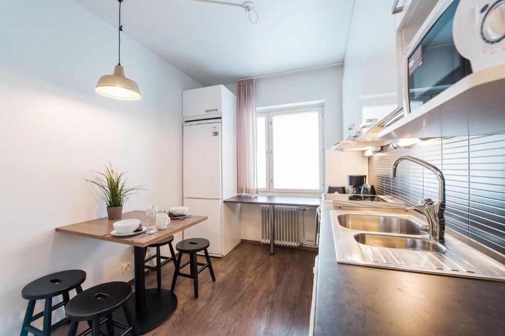 a kitchen with a sink and a table with stools at Forenom Serviced Apartments Helsinki Lapinlahdenkatu in Helsinki