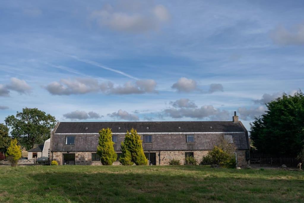 a large brick building in a field with trees at Woodside Barn Stunning 7 bed Barn conversion in Newmachar
