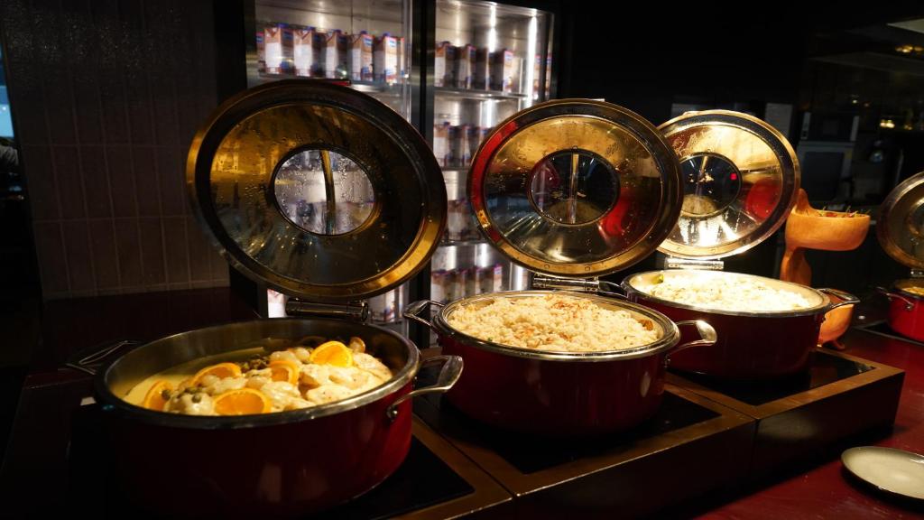 Open buffet dishes sit in covered warming pots on a restaurant counter.