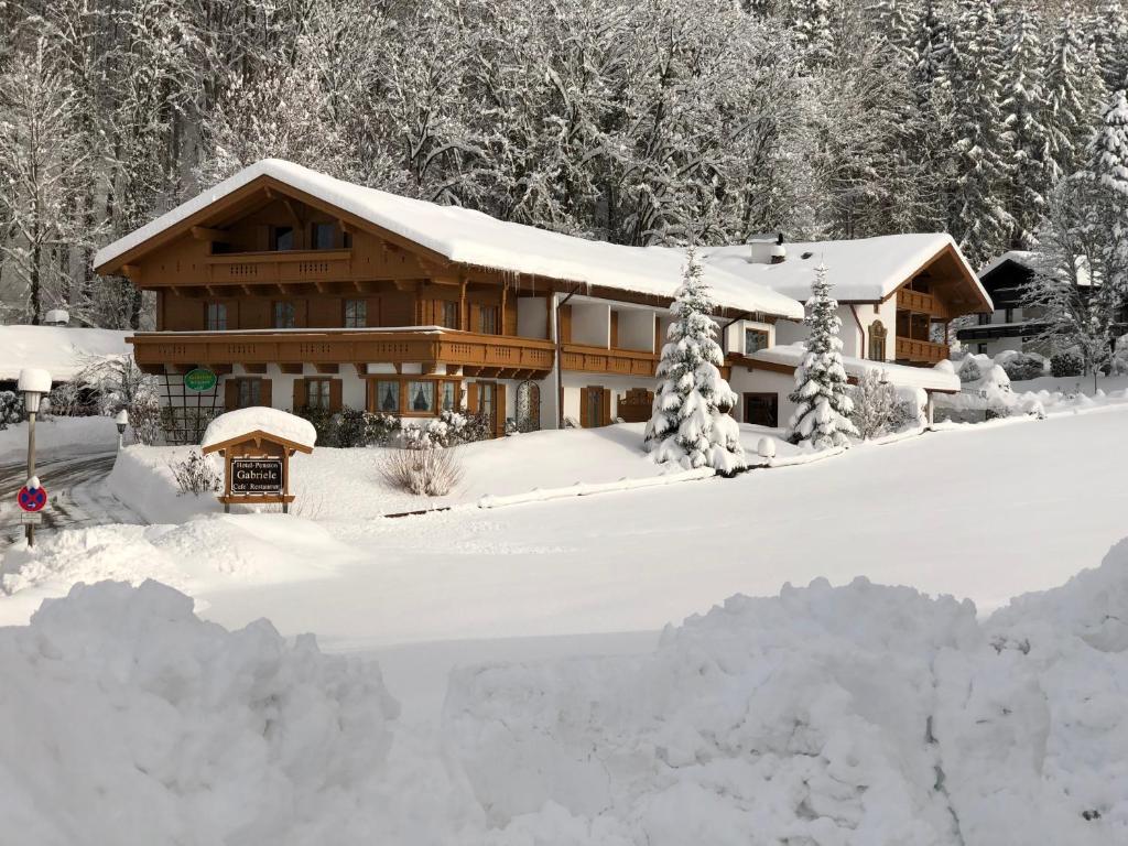 a house covered in snow with a pile of snow at Landhotel Gabriele in Unterwössen