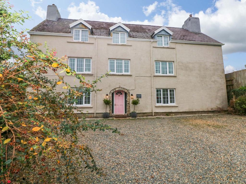 una gran casa de ladrillo con una puerta rosa en Norchard Farm House, en Tenby