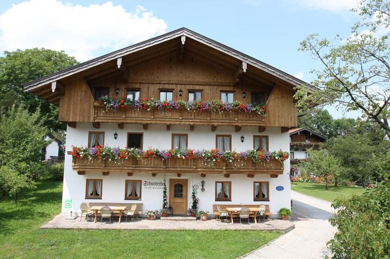 ein Gebäude mit einem Balkon mit Blumen darauf in der Unterkunft Schusterhof Urlaub auf dem Bauernhof in Bernau am Chiemsee