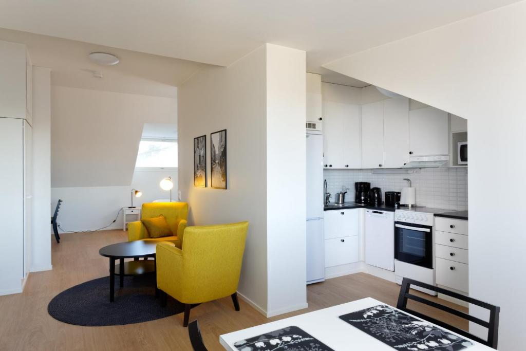 a kitchen and living room with a yellow chair and a table at Forenom Serviced Apartments Helsinki Kruununhaka in Helsinki