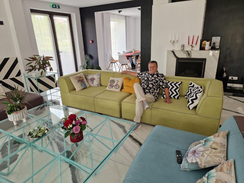 a man sitting on a couch in a living room at Niro Residence in Gura Humorului