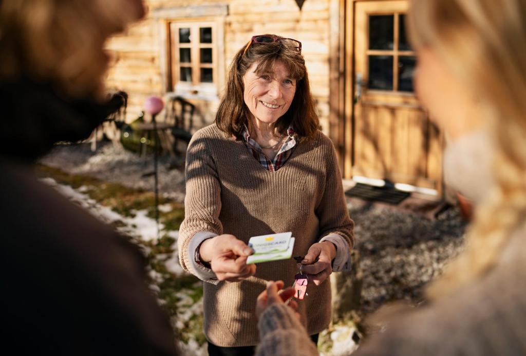 a woman is holding a name card in front of a house at Auszeit-Biohof Neihausmo in Böbing