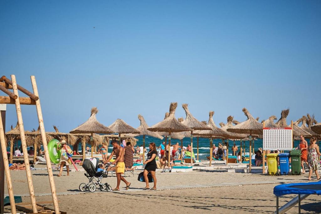a group of people on a beach with umbrellas at Nordis 20 Deluxe Room Mamaia Nord in Mamaia Sat/Năvodari