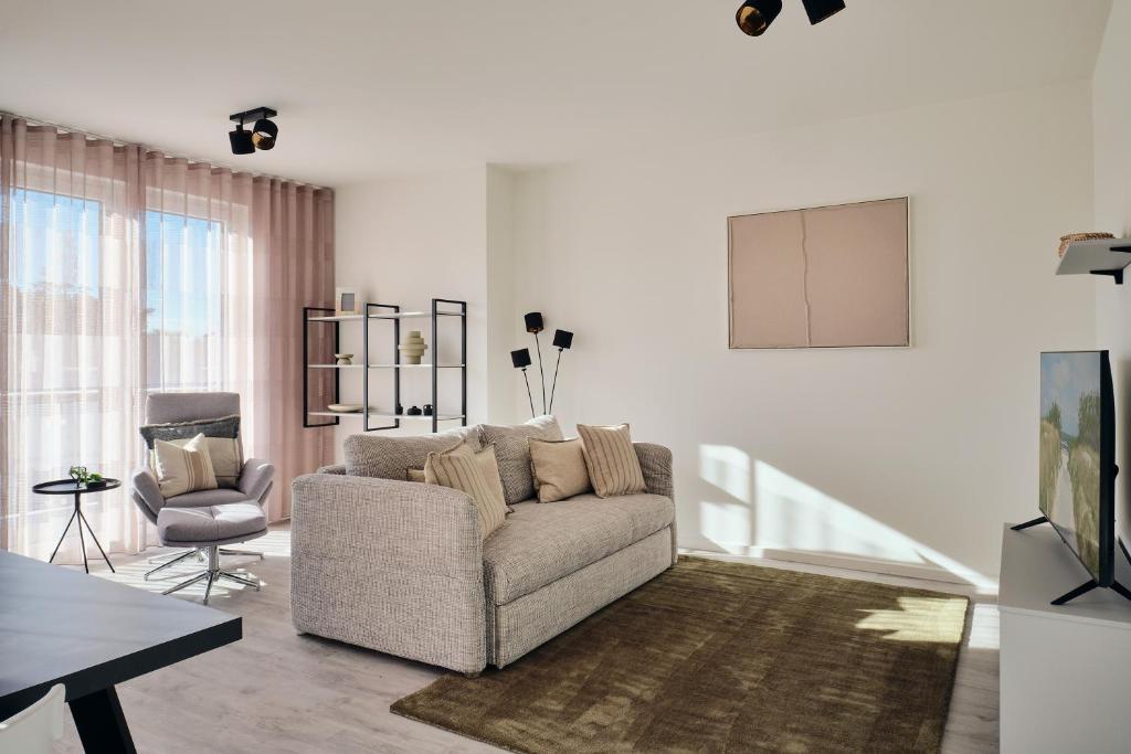 a living room with a couch and a chair at Apartment C13 mit Balkon & Nutzung der Wellness- & Aktivbereiche im "Pine Hill Resort" in Zirchow