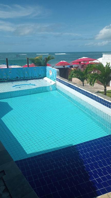 a swimming pool with a blue tile floor and the ocean at Pousada in Porto De Galinhas
